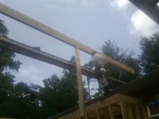 Carpenter setting a ridge beam over a new addition frame — Ice Dam Removal by Roofing Brothers in Boston