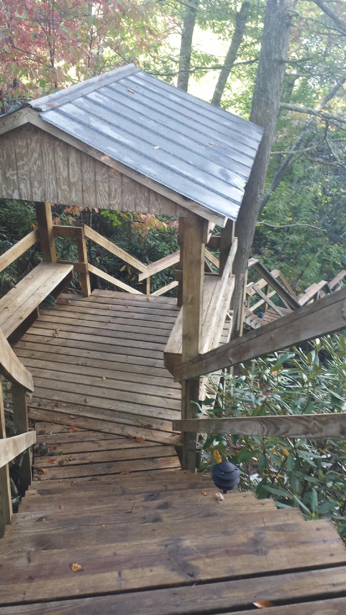 Metal roofed shelter over wooden steps on a wooded walkway — Skylight Repair & Installation work by our crew in Boston
