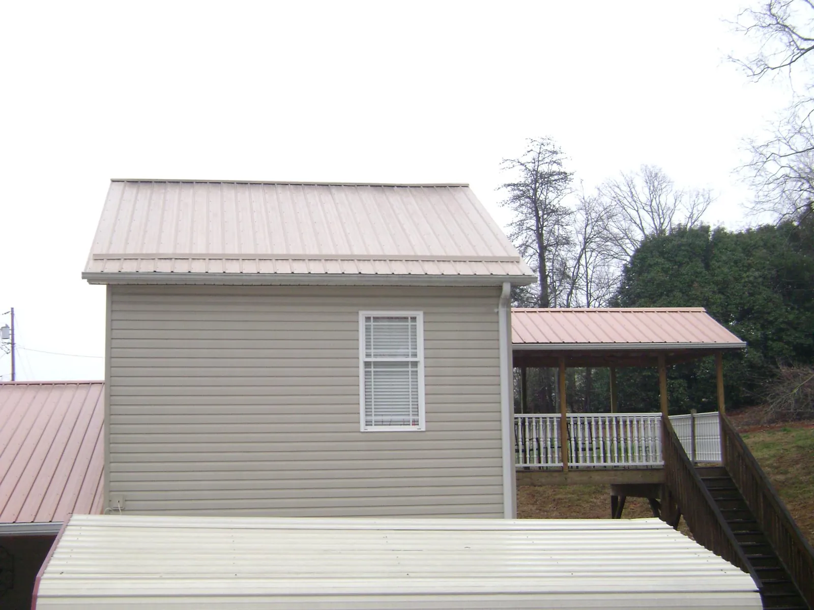 Tan metal roofs on a two story addition and attached porch, from a Roof Replacement job in Boston